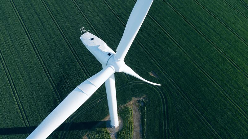 Wind turbine seen from above over green fields
