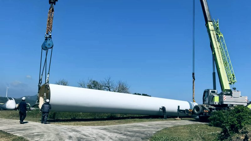 Blade on the ground beside a crane before lifting